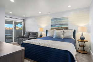 Carpeted bedroom with access to exterior, recessed lighting, and wood walls
