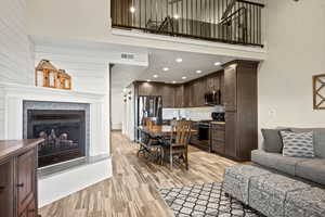Living area featuring a high ceiling, a glass covered fireplace, light wood-type flooring, and recessed lighting