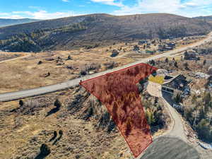 Aerial view of property and surrounding area featuring property parcel outlined and a mountain backdrop