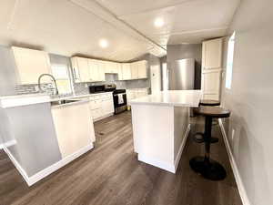 Kitchen with a breakfast bar, white cabinetry, stainless steel appliances, decorative backsplash, and a kitchen island