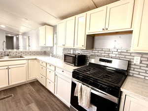 Kitchen featuring stainless steel appliances, decorative backsplash, light stone countertops, and dark wood finished floors