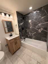 Bathroom featuring tub / shower combination, vanity, and light marble finish floors