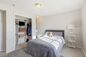 Carpeted bedroom featuring a closet and baseboards