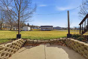 View of grassy yard with a trampoline and a shed
