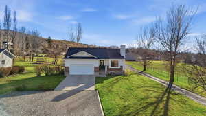 View of front of property featuring driveway, brick siding, a chimney, and an attached garage