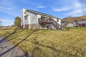 Back of house featuring stairway, a yard, a wooden deck, and a chimney