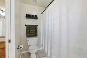 Bathroom with curtained shower and light tile patterned floors