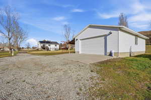 View of side of home featuring an outbuilding, a lawn, a garage, and driveway