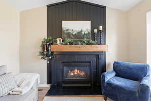 Sitting room with vaulted ceiling, wood finished floors, and a glass covered fireplace