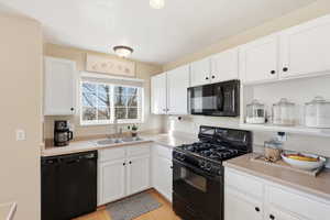 Kitchen with black appliances, white cabinets, and light countertops