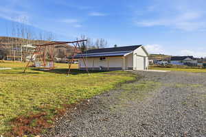 View of home's exterior with a yard, a garage, gravel driveway, and covered porch