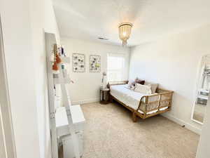 Bedroom featuring light carpet and a textured ceiling