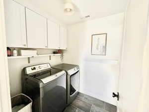 Laundry room with washing machine and dryer, cabinet space, and dark tile patterned floors