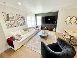 Living room featuring light wood-style flooring, a textured ceiling, and recessed lighting