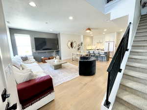 Living room featuring stairs, a textured ceiling, recessed lighting, and light wood-type flooring