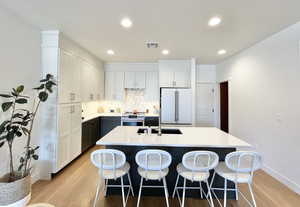 Kitchen with white cabinetry, premium appliances, an island with sink, recessed lighting, and a kitchen bar