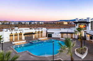 Pool at dusk featuring a patio, a pool with connected hot tub, a pergola, and a mountain view