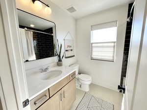 Full bathroom with vanity, tiled shower, and light tile patterned flooring