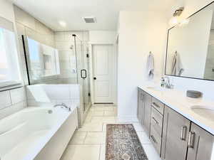 Full bath with a garden tub, double vanity, a shower stall, and light tile patterned flooring