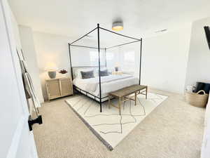 Bedroom featuring a textured ceiling and light carpet
