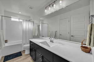 Bathroom with shower / bath combination with curtain, light wood-style flooring, and vanity