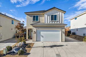 View of front facade featuring a garage, a tiled roof, and concrete driveway