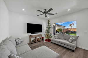 Living room with wood finished floors, ceiling fan, and recessed lighting