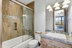 Bathroom with connected bathroom, bath / shower combo with glass door, and vanity