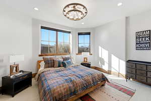 Carpeted bedroom with recessed lighting and a chandelier
