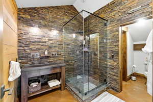 Full bathroom featuring finished concrete flooring, lofted ceiling, a shower stall, and vanity