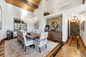 Dining space featuring a chandelier, a wooden ceiling with exposed beams, a wall unit AC, light wood-type flooring, and high vaulted ceiling