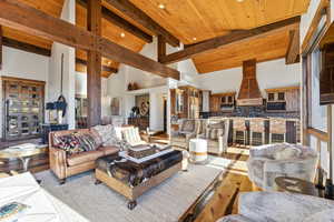Living room with high vaulted ceiling, beam ceiling, healthy amount of natural light, and hardwood / wood-style floors