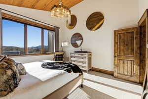 Bedroom with vaulted ceiling, carpet, a chandelier, wooden ceiling, and a mountain view