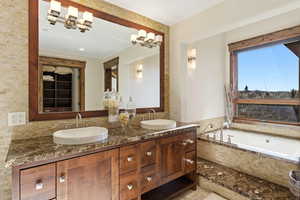 Full bath with double vanity, a garden tub, and a chandelier