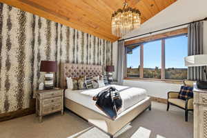 Carpeted bedroom featuring lofted ceiling, a chandelier, and wooden ceiling