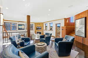 Living area featuring stairway, wood walls, a glass covered fireplace, crown molding, and recessed lighting