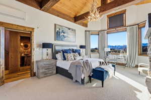 Bedroom featuring a wooden ceiling with exposed beams, a wall mounted AC, carpet flooring, a mountain view, and a chandelier