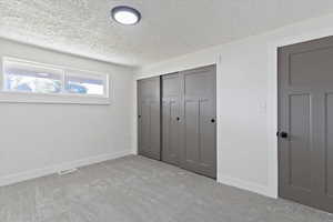 Unfurnished bedroom with carpet floors, a closet, and a textured ceiling