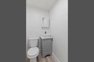 Half bath with light wood-type flooring and vanity