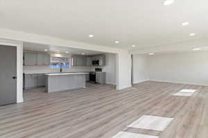 Kitchen with gray cabinetry, open floor plan, light countertops, and recessed lighting
