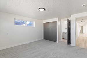 Unfurnished bedroom with a closet, a textured ceiling, and light carpet