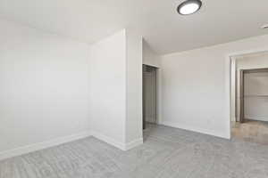Unfurnished bedroom with light carpet and baseboards
