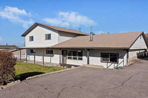 View of front of house featuring a shingled roof, stone siding, and a front lawn