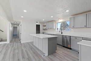 Kitchen featuring gray cabinetry, recessed lighting, stainless steel dishwasher, open shelves, and light wood-style floors