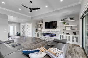 Living area featuring light wood-style floors, built in features, recessed lighting, a ceiling fan, and a stone fireplace