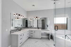 Bathroom featuring double vanity, a shower stall, and a garden tub
