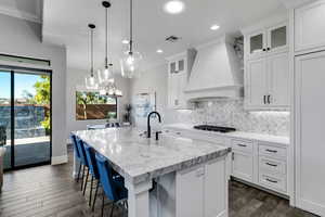 Kitchen featuring hanging light fixtures, white cabinets, an island with sink, dark wood-style flooring, and recessed lighting