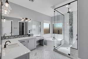 Bathroom with a garden tub, a marble finish shower, double vanity, and two vanities