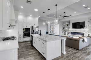 Kitchen with white cabinetry, crown molding, a fireplace, decorative backsplash, and decorative light fixtures