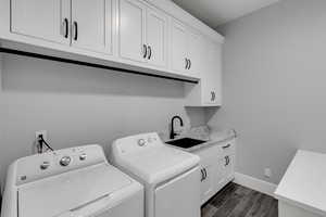 Washroom with wood finish floors, cabinet space, and separate washer and dryer